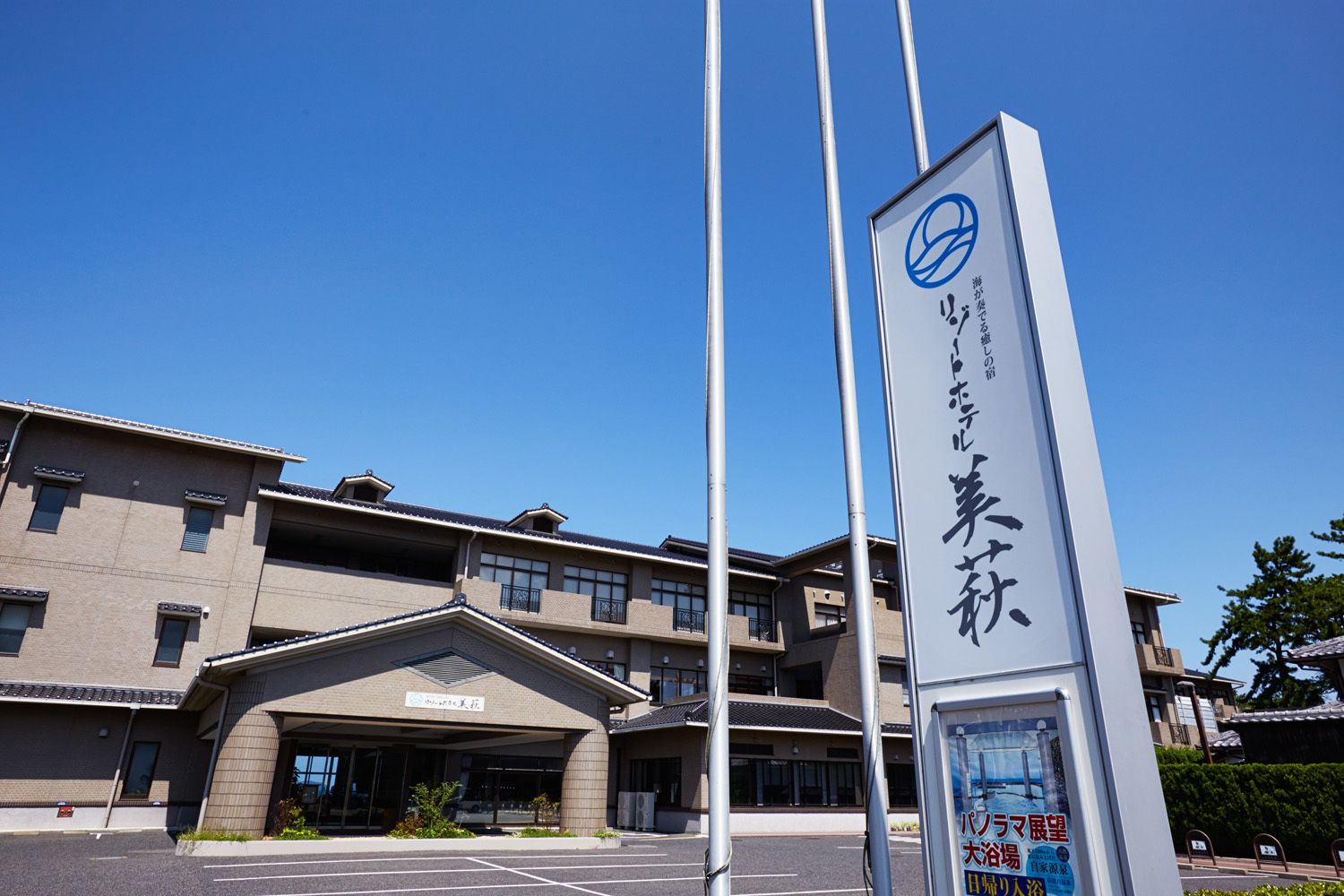 A building with a signboard and a parking lot.
