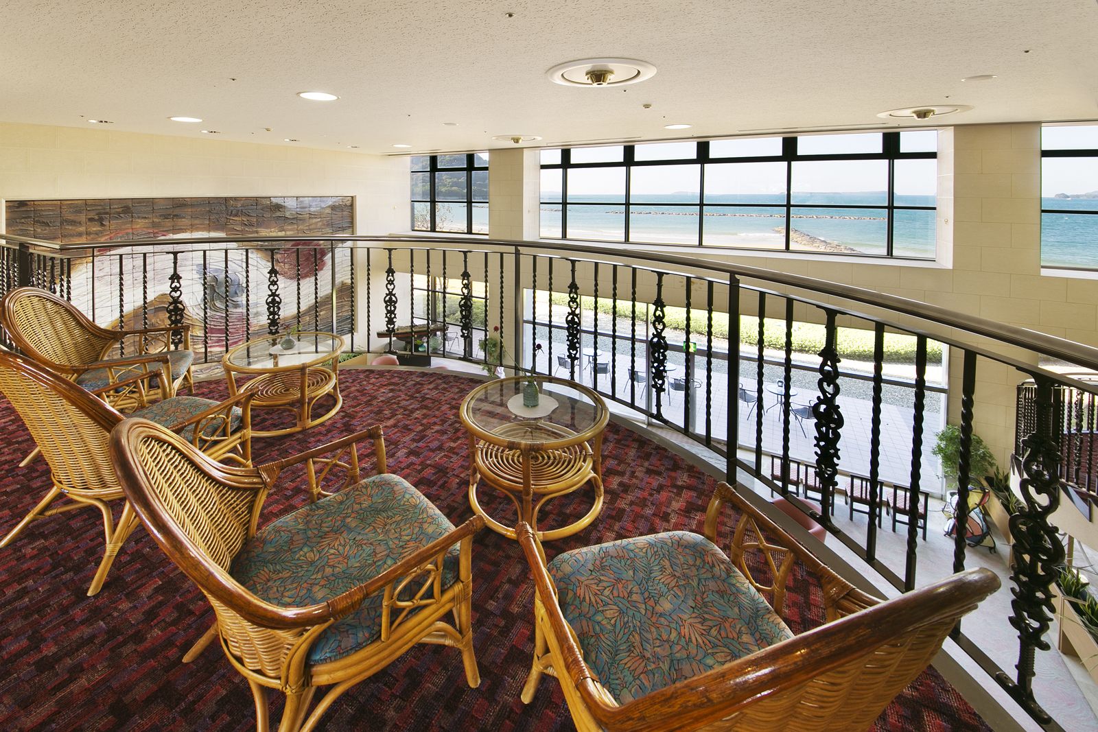 A balcony with wicker furniture and a view of the beach.