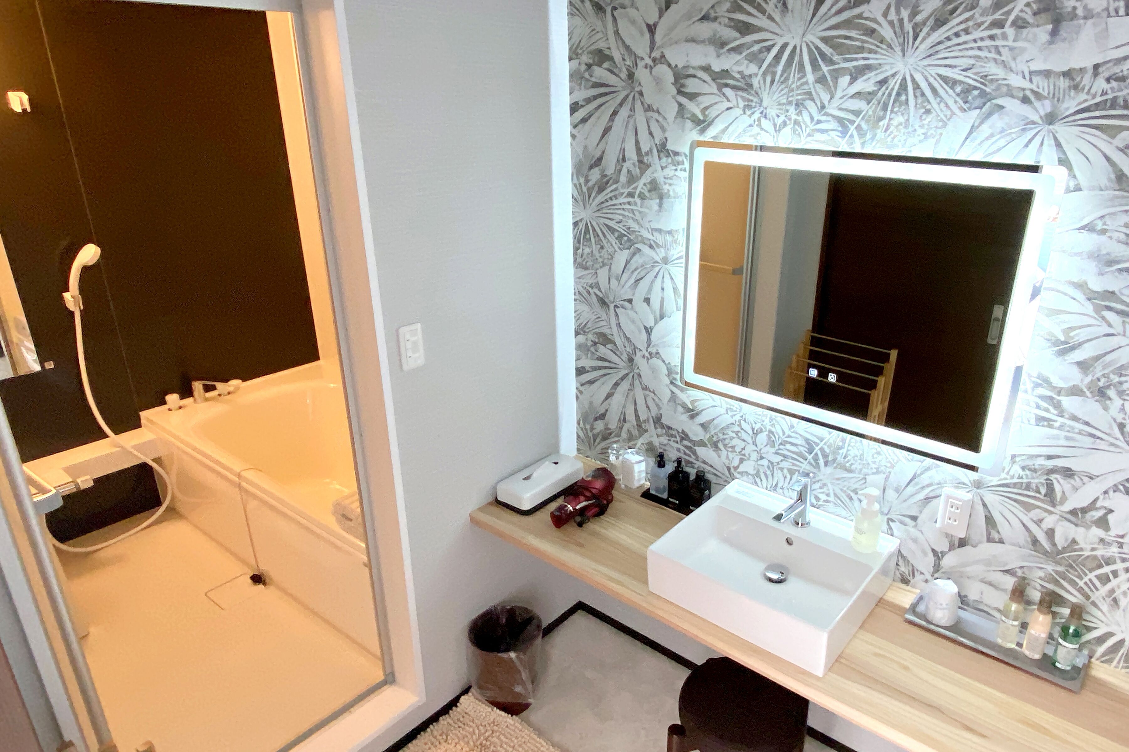 A bathroom with a bathtub, a sink with a mirror, and a shelf with toiletries.