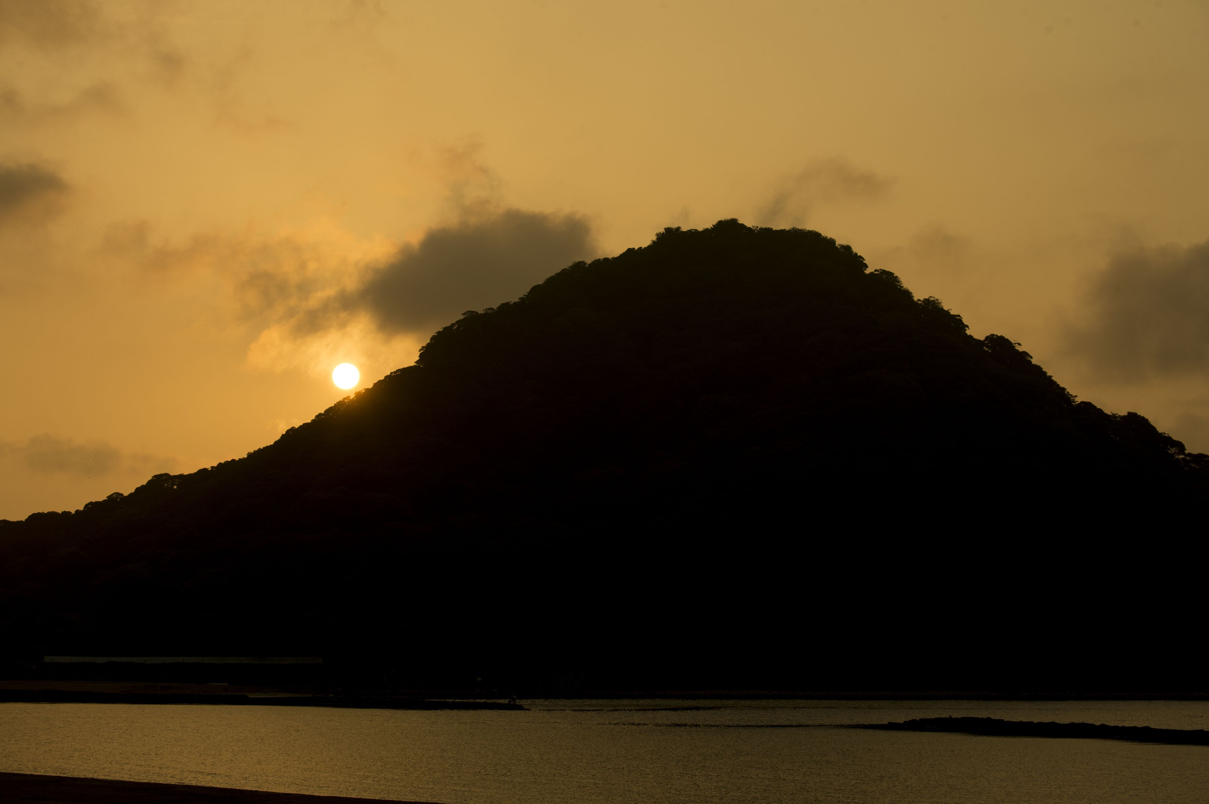A mountain silhouette with the sun setting behind it.