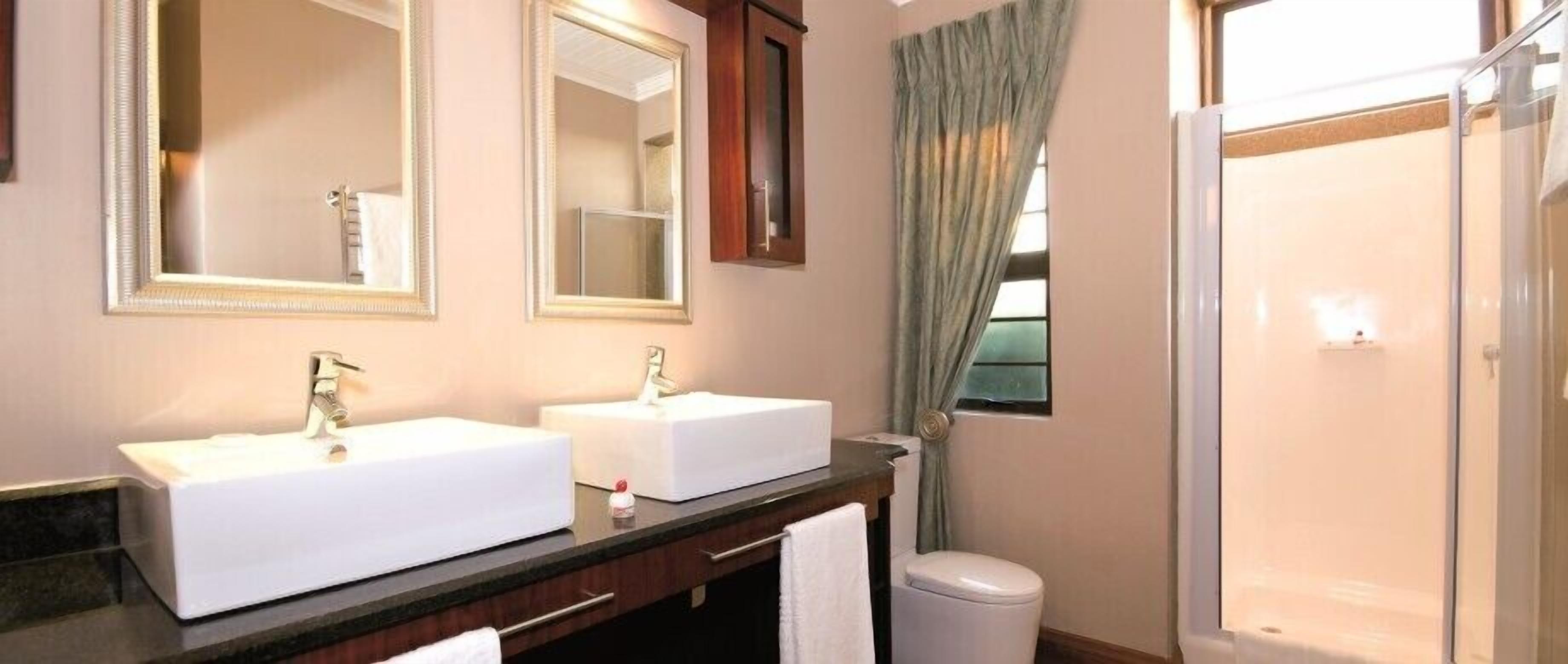 A bathroom with two sinks, a mirror, a cabinet, a towel, and a shower.