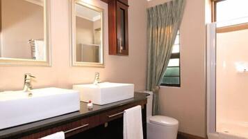 A bathroom with two sinks, a mirror, a cabinet, a towel, and a shower.