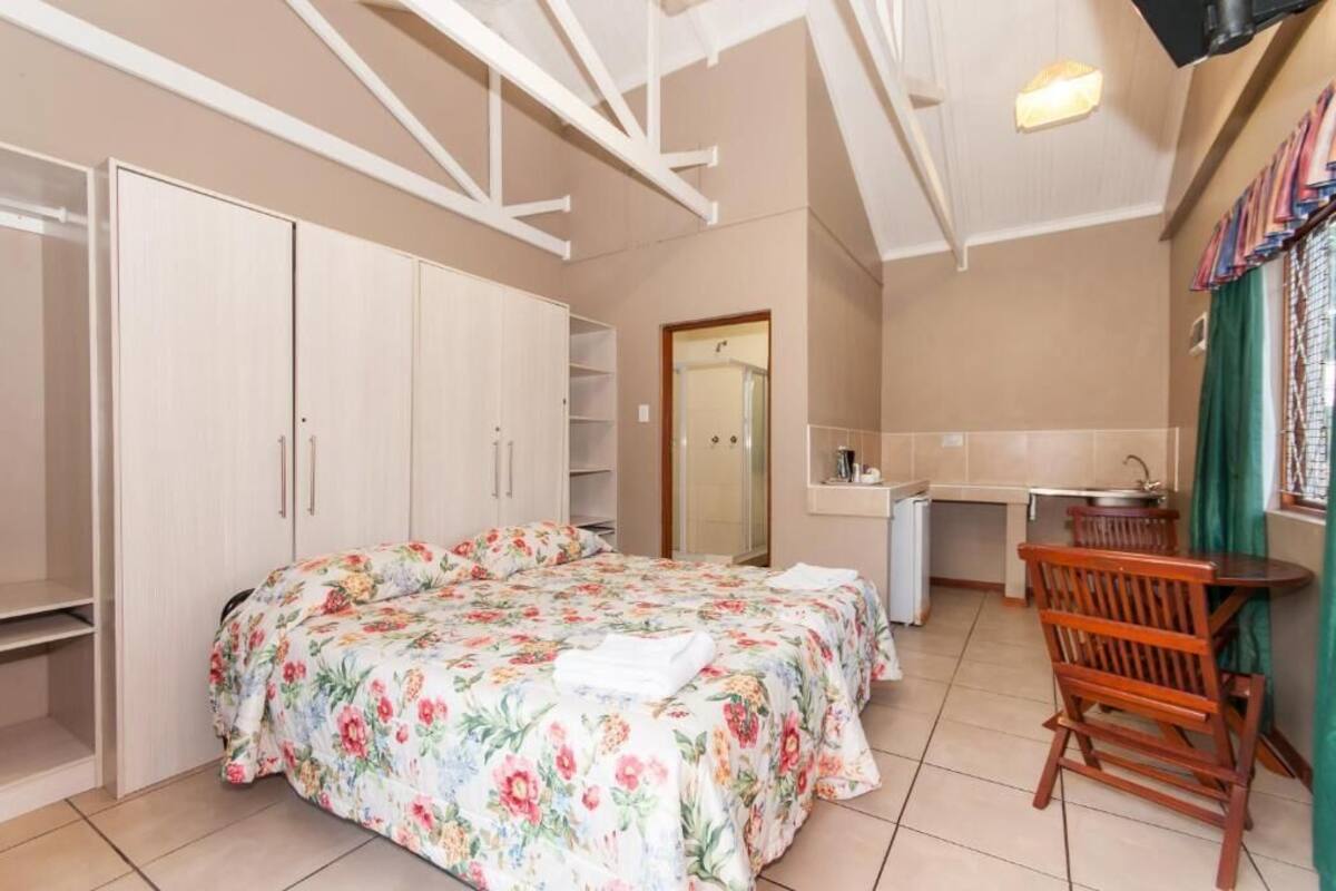 A bedroom with a bed, a desk, and a chair.
