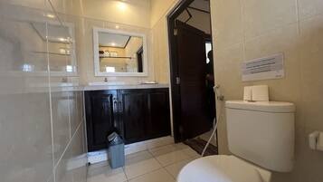 A bathroom with a white toilet, a sink with a mirror above it, and a trash bin.