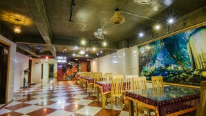 Ein Restaurant mit Schachbrettfußboden, Holztischen mit Glasplatten und einer Wandmalerei einer Höhle.