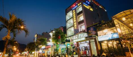 A multi-story building with illuminated signage, including a hotel and a shop.