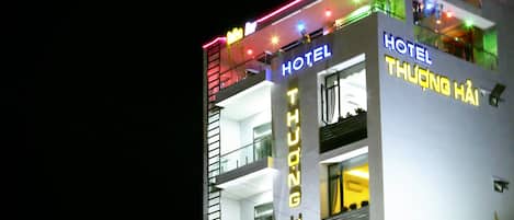 A multi-story hotel with illuminated signage, balconies, and a visible shop at the ground level.