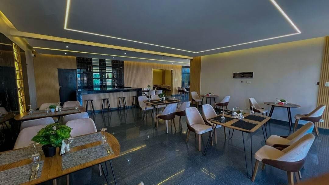 A modern restaurant with a bar area, multiple seating arrangements, and a contemporary interior design.