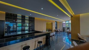 Un área de bar moderna con mostrador negro, taburetes y vistas al exterior.