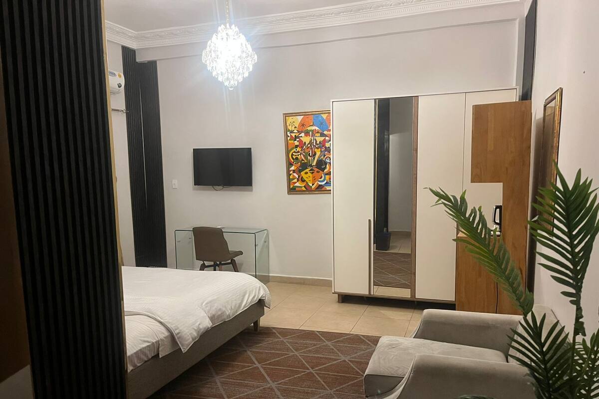 A hotel room with a bed, a desk, a TV, a wardrobe, and a mirror.