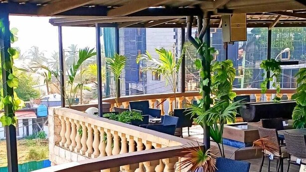 Un espacio al aire libre con suelo de madera, asientos acolchados y barandilla.