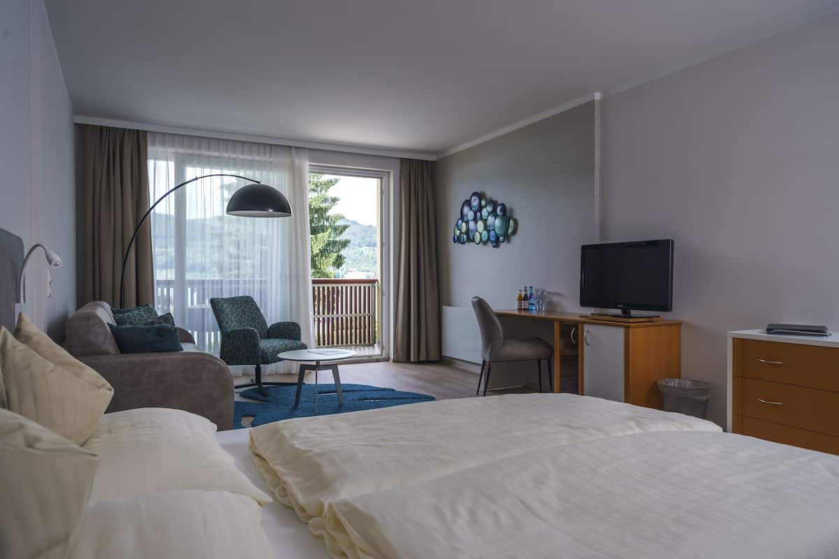 Een hotelkamer met een bed, een bureau, een televisie, een stoel en uitzicht op de omgeving.