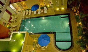 An aerial view of a swimming pool with lounge chairs and umbrellas.