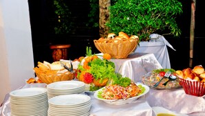 A buffet table with various dishes, plates, and a basket of bread. - Peacock Heritage Anuradhapura (Anuradhapura)