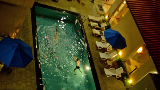 A swimming pool with people swimming, lounge chairs, and umbrellas. - Peacock Heritage Anuradhapura (Anuradhapura)