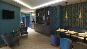 Un moderno vestíbulo de hotel con zona de bar, asientos y una pantalla de televisión.