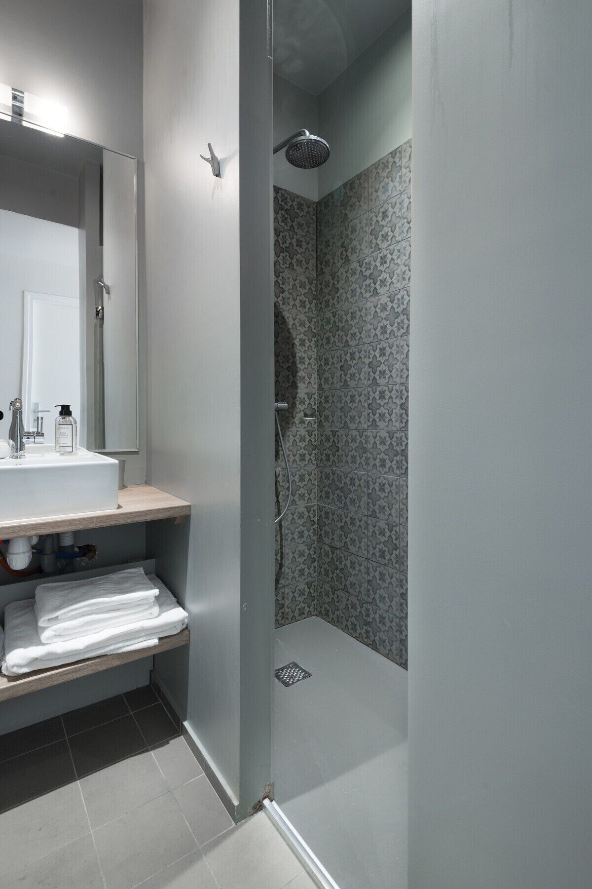A modern bathroom with a sink, mirror, and shower.