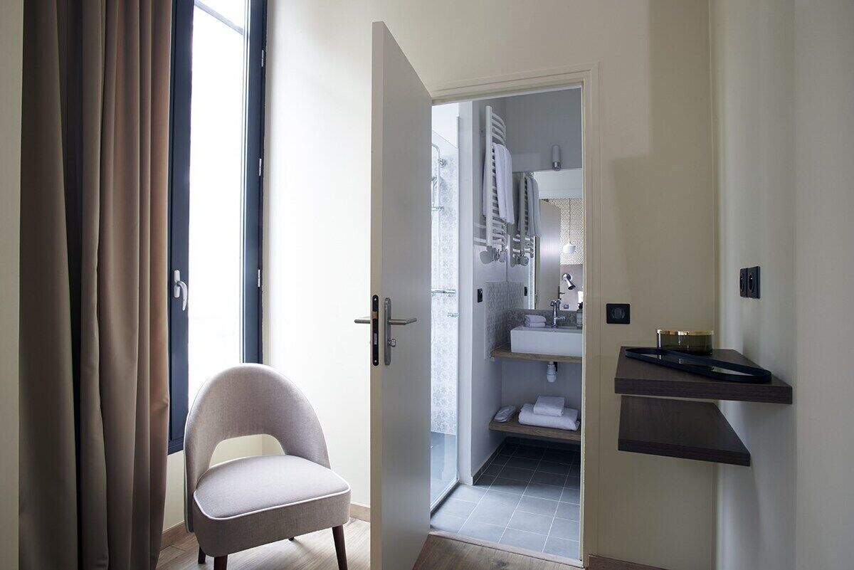 A modern bathroom with a shower, a sink, and a towel rack.