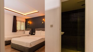 A hotel room with two beds, a bathroom with black tiles, and a modern design.