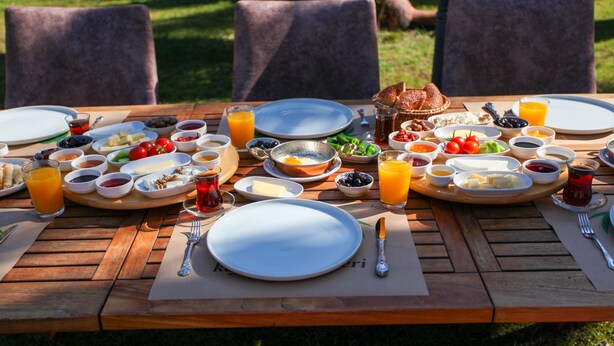 A wooden table set with breakfast items including eggs, toast, fruit, and beverages.