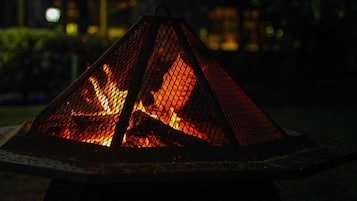 Een vuurkorf met een metalen omheining, gelegen in een openluchtomgeving.