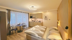 Une chambre d’hôtel de taille réduite, comprenant un lit, un petit bureau, une chaise et une kitchenette.