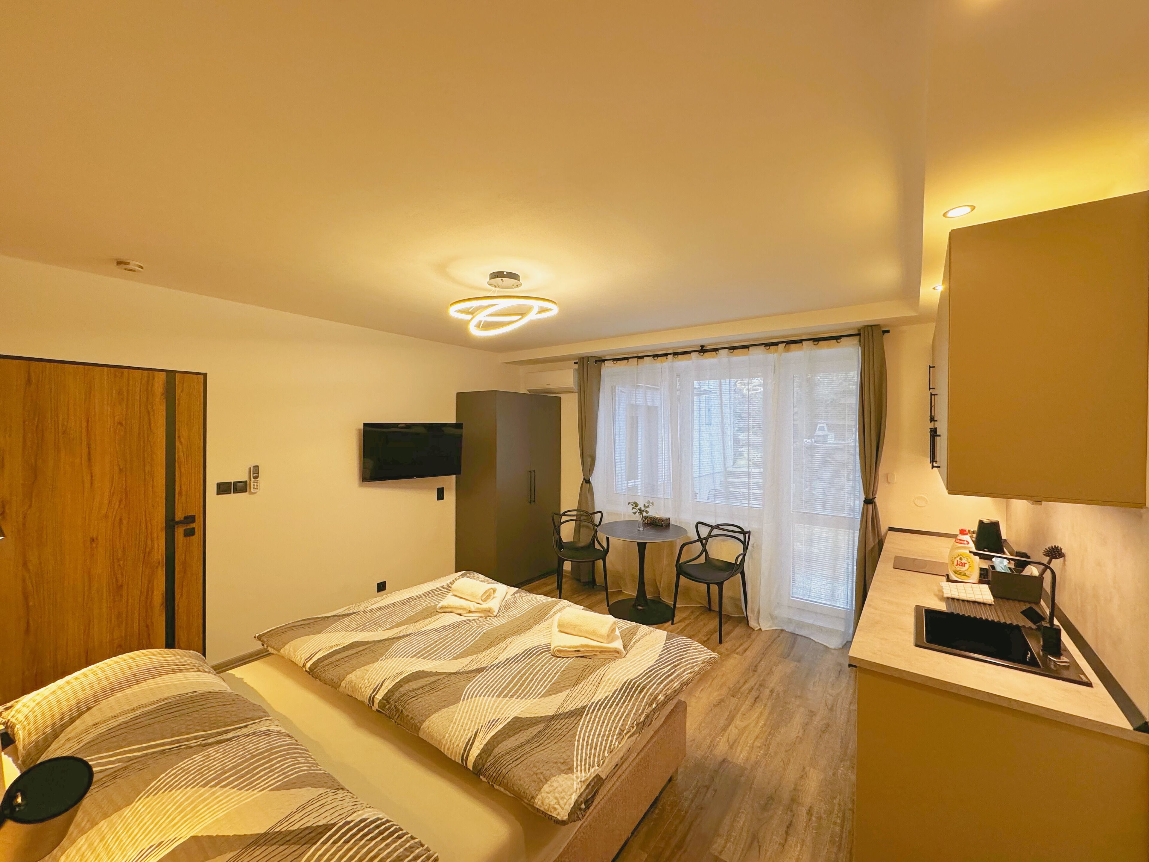 A hotel room with a bed, a desk, a chair, a television, and a window with curtains.