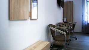 Une chambre d’hôtel moderne, dotée d’une commode en bois, d’un téléviseur fixé au mur et d’un coin salon avec des fauteuils et une table.