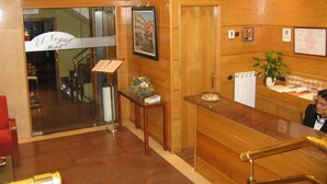 A hotel reception area with a wooden interior, a reception desk, a framed picture on the wall, and a sign for 'El Nacional Hotel'. - El Nogal (Valladolid)