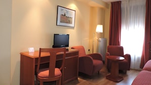 A hotel room with a desk, two chairs, a TV, a lamp, and a window with curtains. - El Nogal (Valladolid)