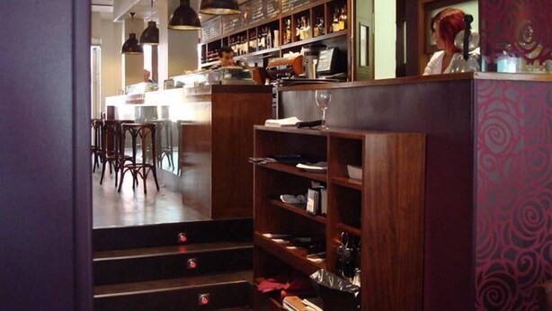 A bar area with wooden shelves, a counter, and hanging pendant lights. - El Nogal (Valladolid)