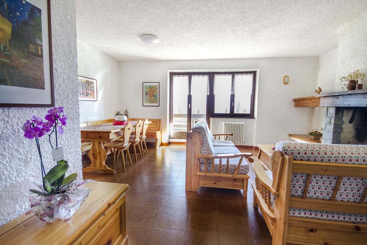 A cozy living room with a fireplace, wooden furniture, and a dining area.