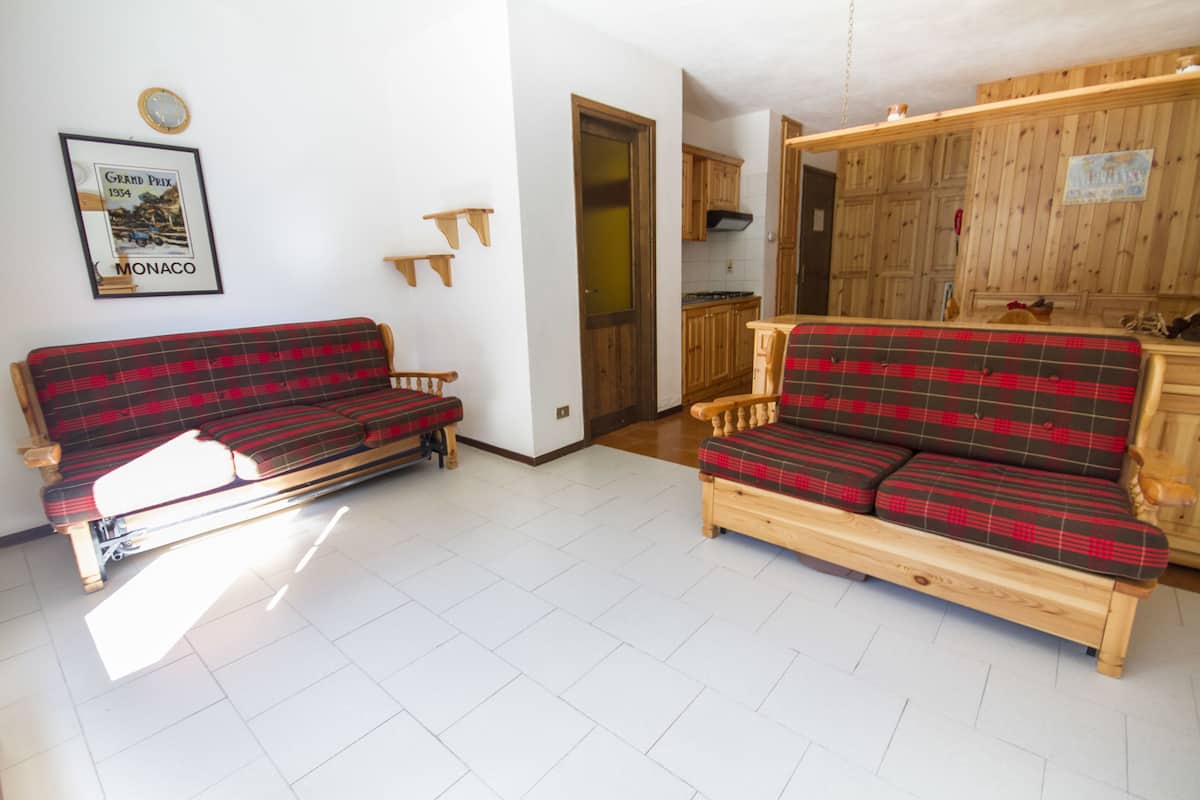 A living room with two red and black plaid sofas, wooden cabinets, and a framed picture on the wall.