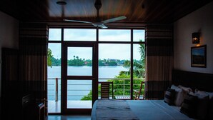 A bedroom with a large window, a ceiling fan, and a bed with pillows. - Riverside Inn Fuji (Bentota)