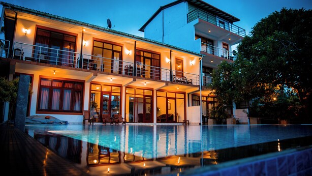 A two-story building with a swimming pool in front. - Riverside Inn Fuji (Bentota)