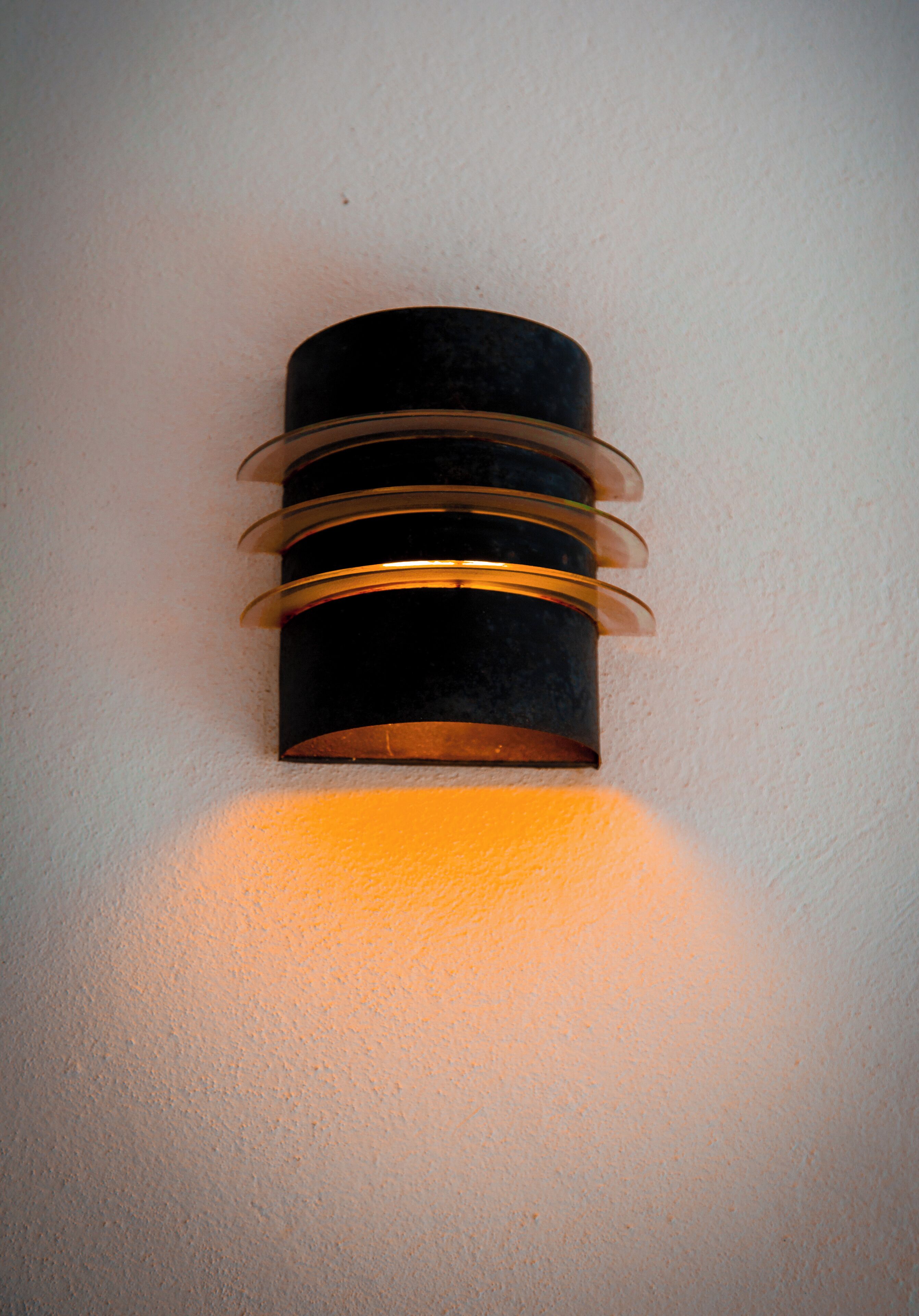 A wall-mounted light fixture with a cylindrical design and horizontal metallic bands.