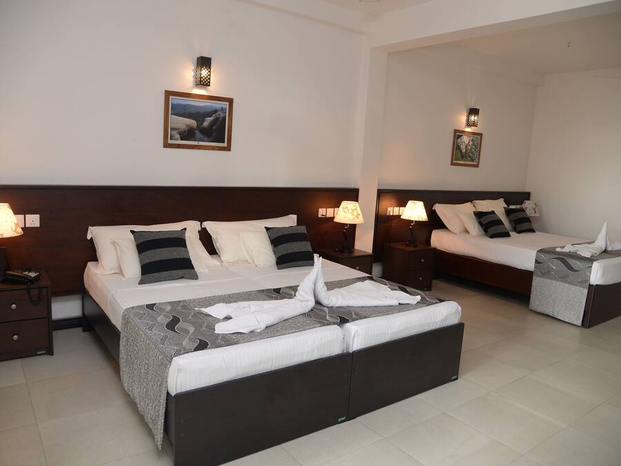 A hotel room with two beds, each with a headboard, bedside tables, lamps, and a framed picture on the wall.