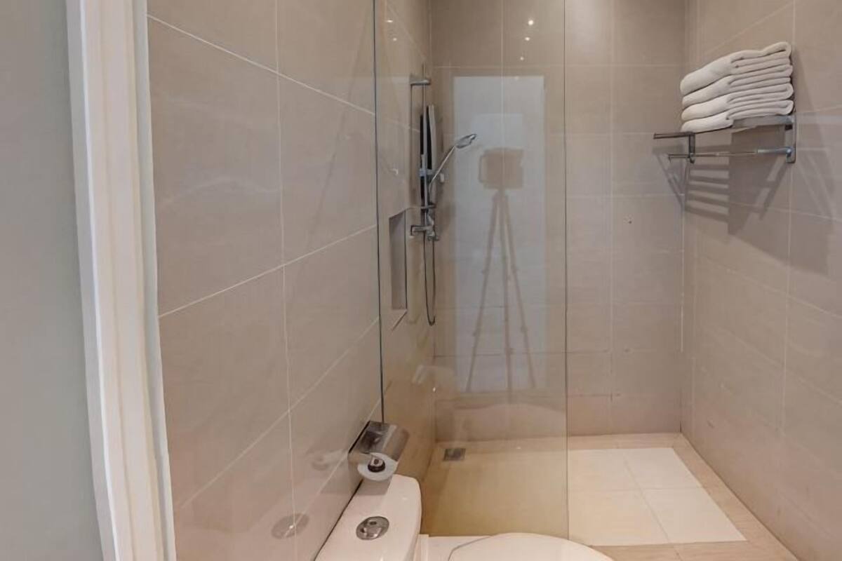 A modern bathroom with a glass shower enclosure, a toilet, and a towel rack.
