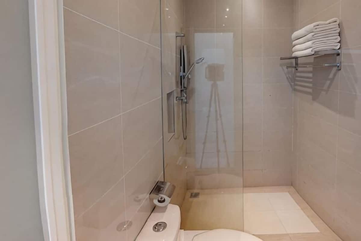 A modern bathroom with a glass shower enclosure, a toilet, and a towel rack.