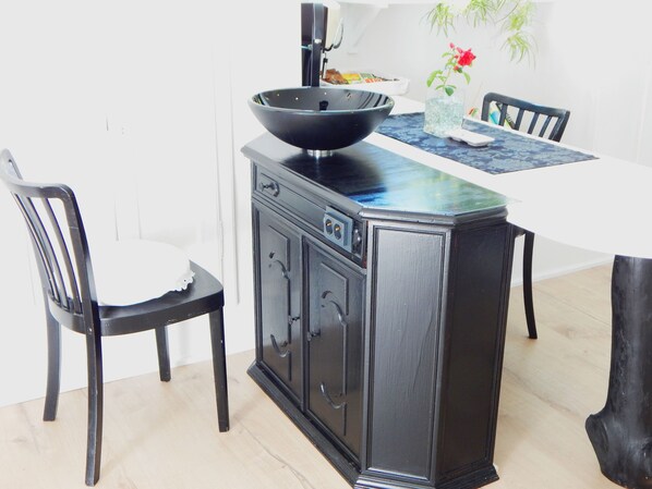 A dining area with a black cabinet, a white table, and two black chairs.