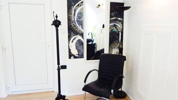 Una habitación con una silla negra, una lámpara de pie y dos espejos fijos en la pared.