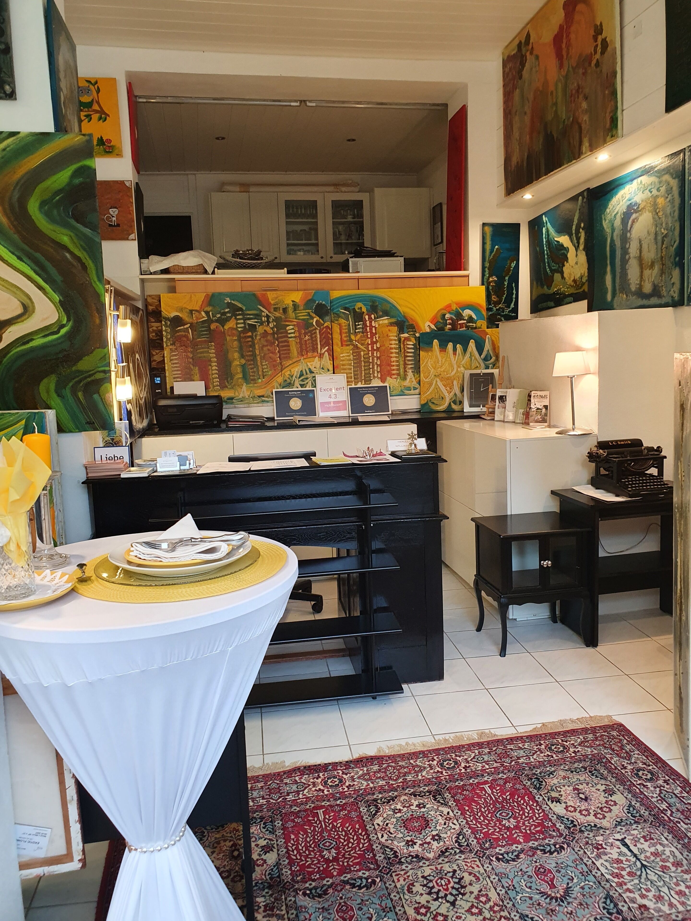 Una cocina moderna con comedor, que presenta una encimera negra, una mesa blanca y una alfombra estampada.