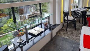 Un espace de restauration moderne avec une balustrade en verre donnant sur un jardin luxuriant.