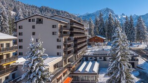 Un hotel de varios pisos con balcones, una pista de esquí y árboles cubiertos de nieve.