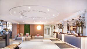 Un moderno vestíbulo de hotel con mostrador de recepción, zona de estar y una pared verde.