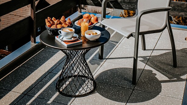 Un balcón con una mesa dispuesta para el desayuno, con vista a un pueblo montañoso.