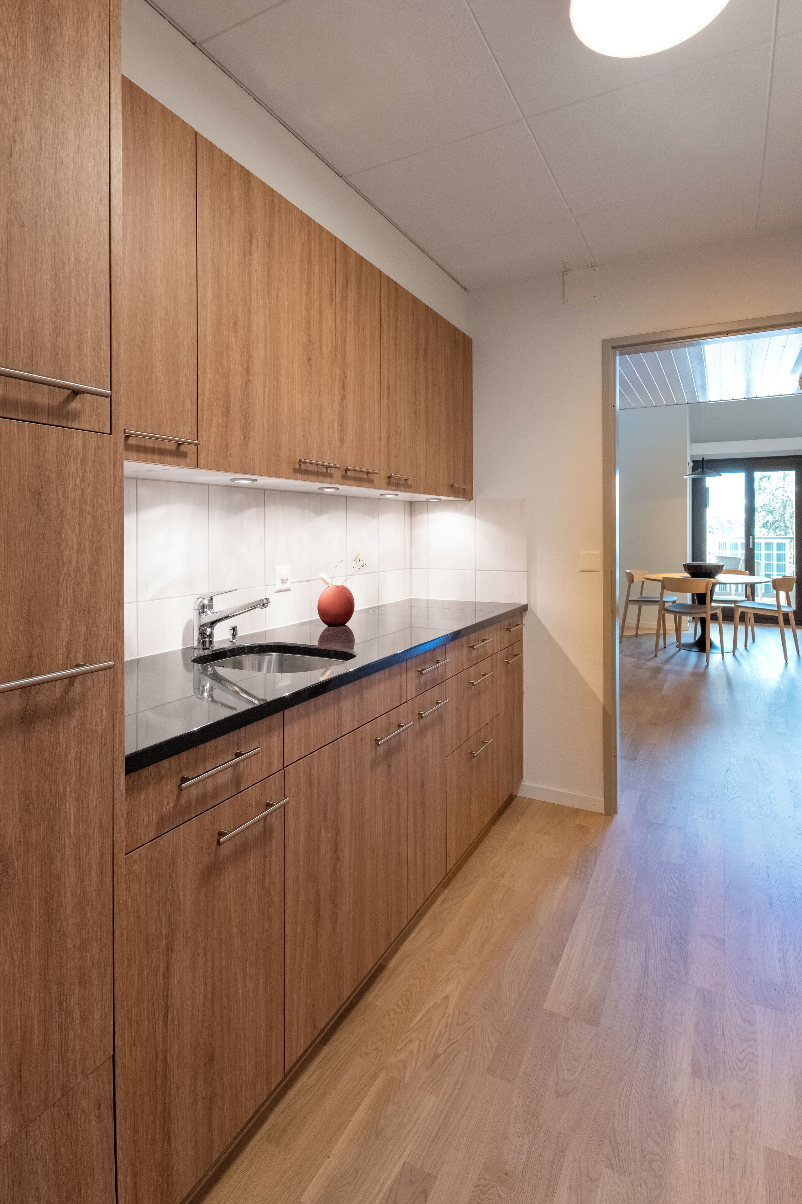 A modern kitchen with wooden cabinets, a black countertop, and a sink.