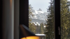 Una habitación con un ventanal que ofrece vistas a montañas nevadas y árboles.