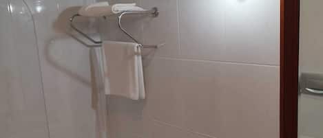 A bathroom with a bathtub, toilet, and sink. There are toiletries on the sink and a towel rack above the toilet.