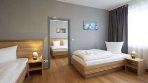 A hotel room with two beds, wooden headboards, bedside tables with lamps, a painting on the wall, and a large window with curtains. - Hotel Weimarer Berg (Apolda)